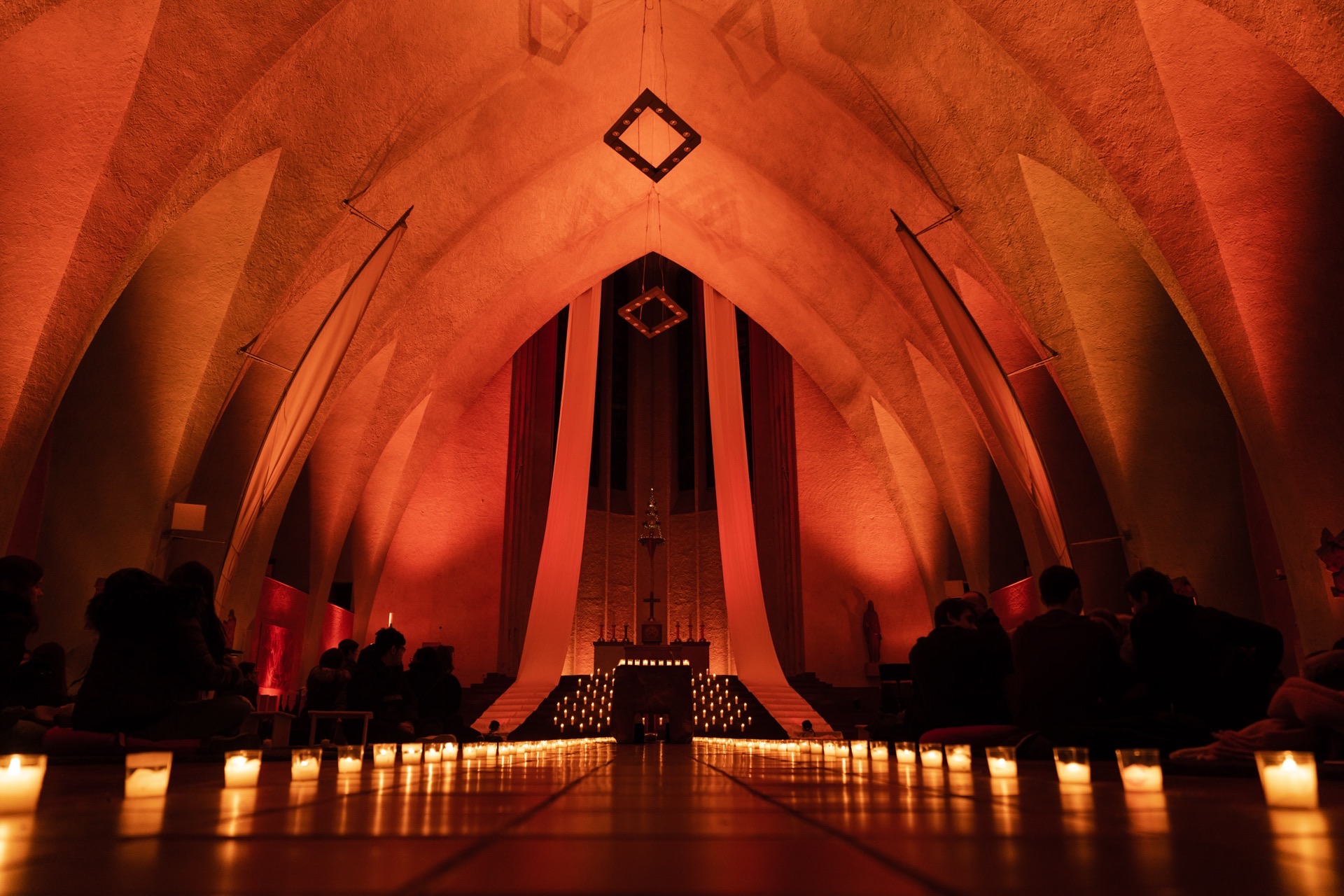 Kircheninnenraum mit roter Beleuchtung und Kerzen