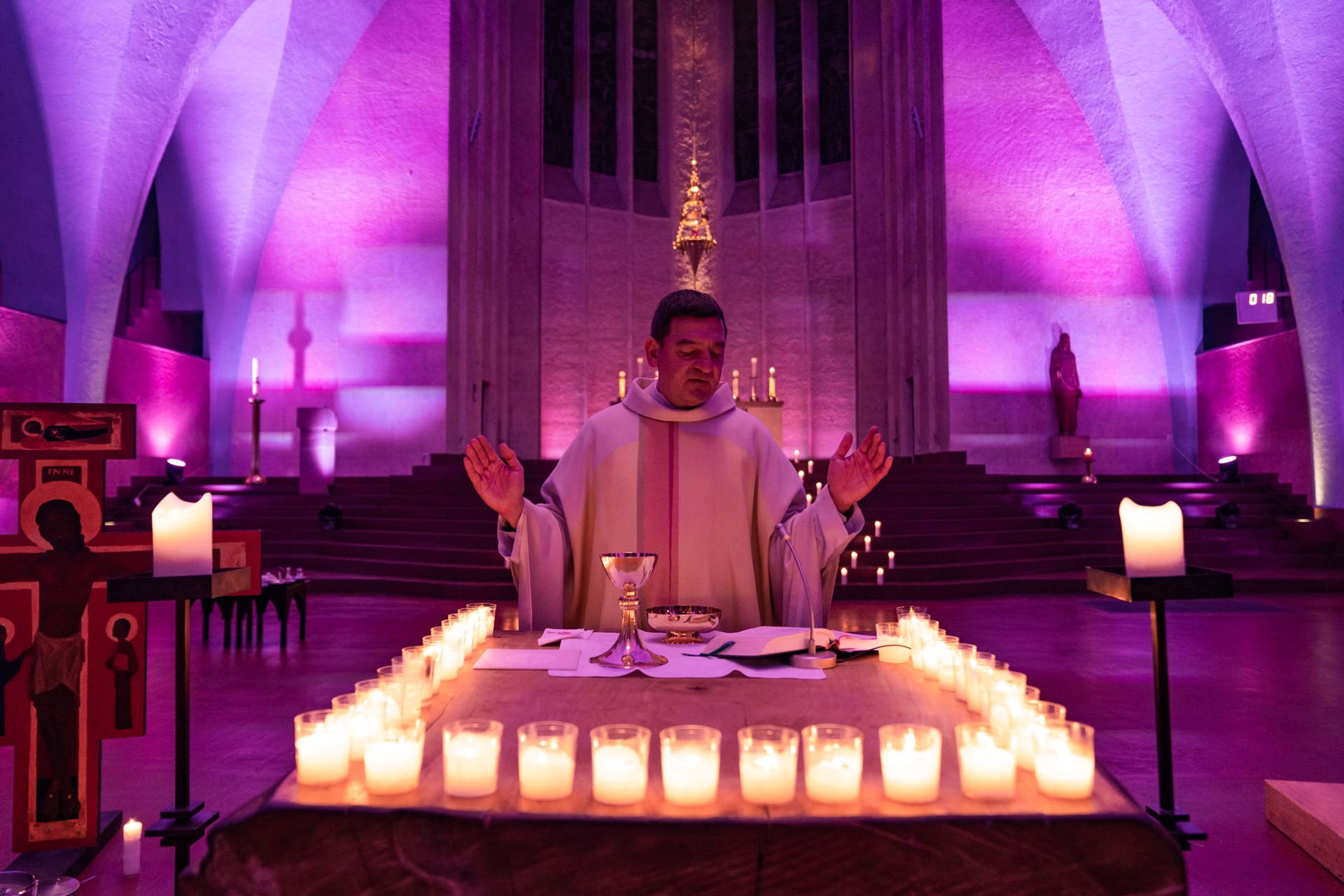 Priester zelebriert Messe bei Kerzenschein in Kirche