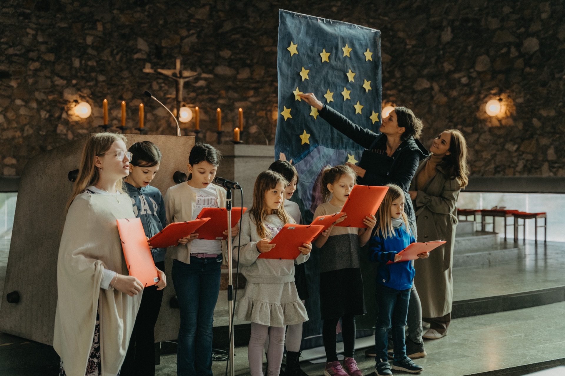 Kinderchor singt vor EU-Flagge in Kirche
