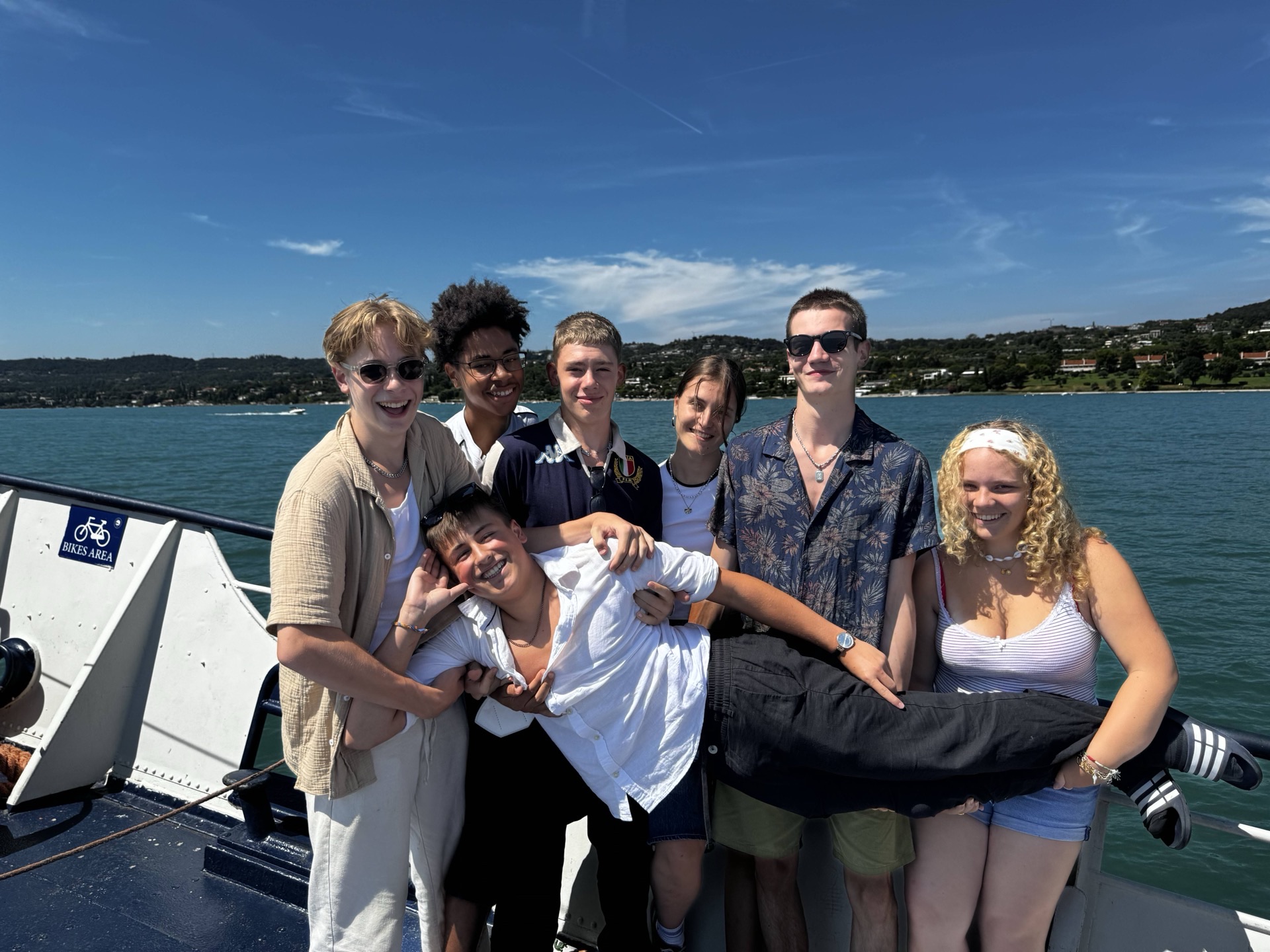 Freundesgruppe auf Boot vor See bei Sonnenschein