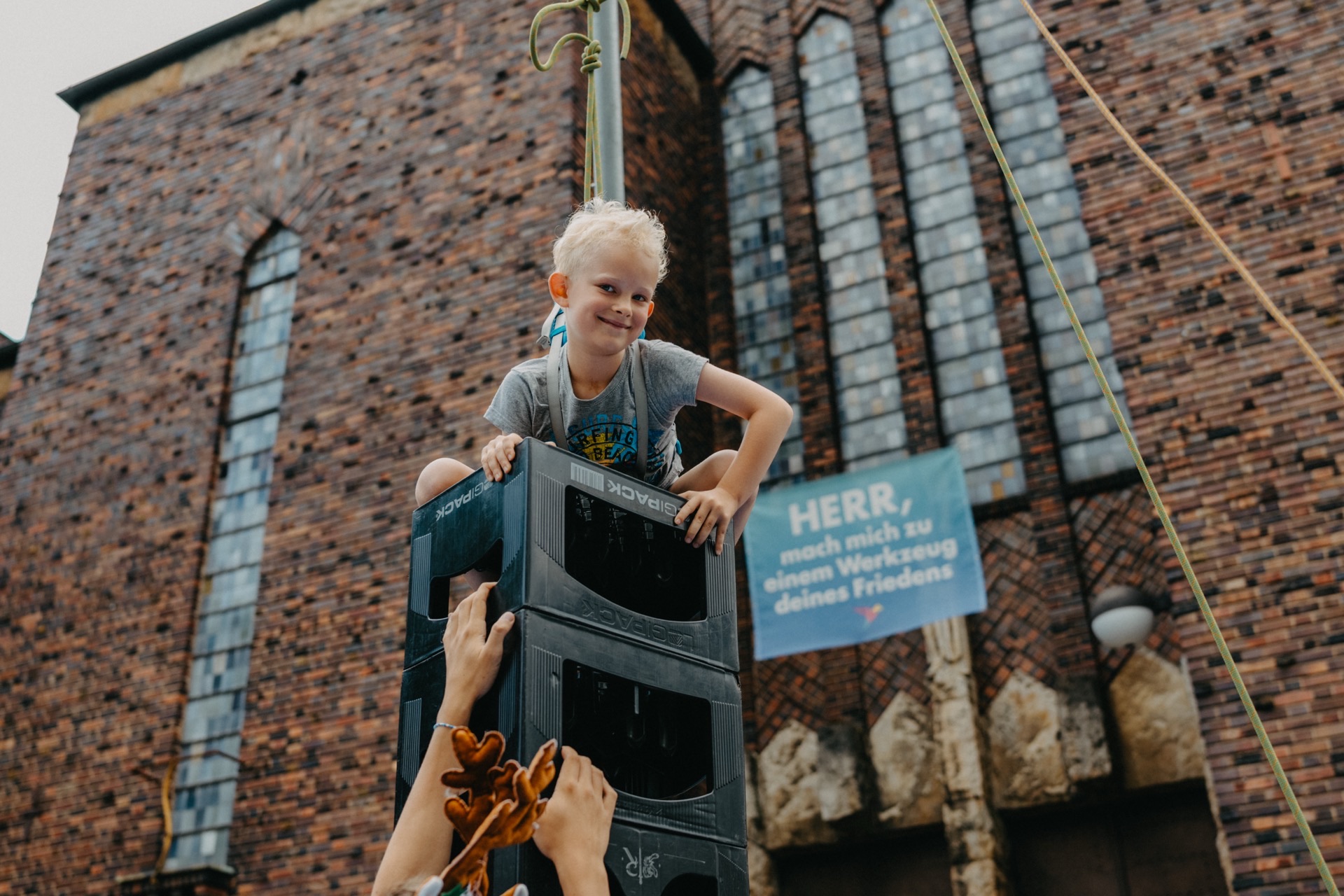 Kind klettert auf gestapelten Kisten vor Kirche