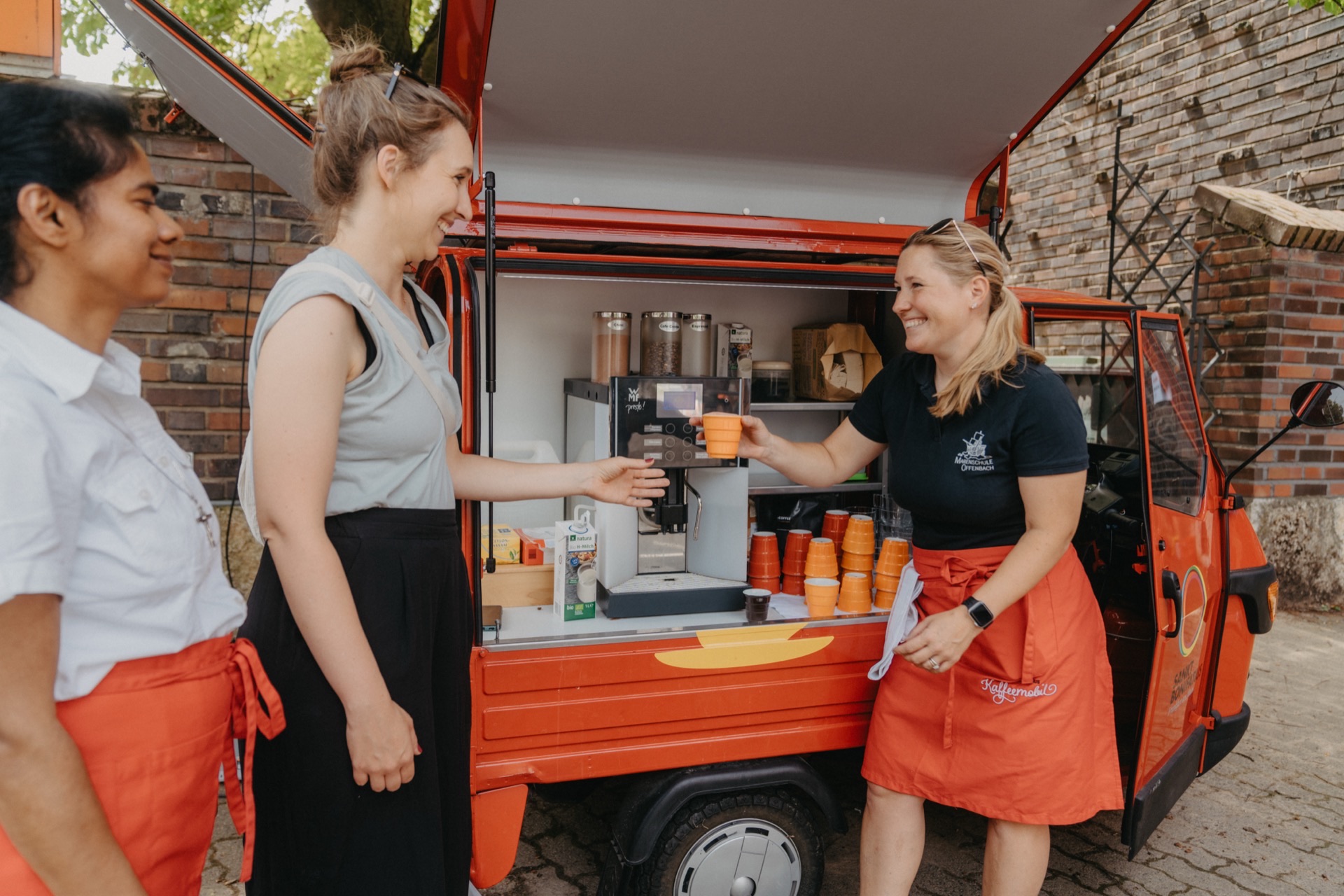 Barista reicht Kundin Kaffee am mobilen Verkaufswagen