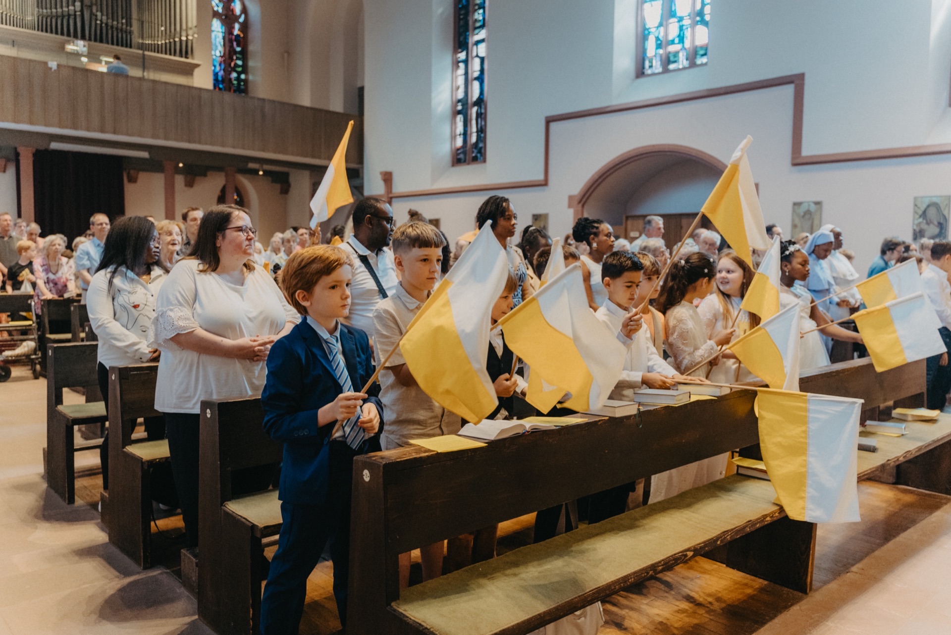Kinder mit gelb-weißen Fahnen in Kirche
