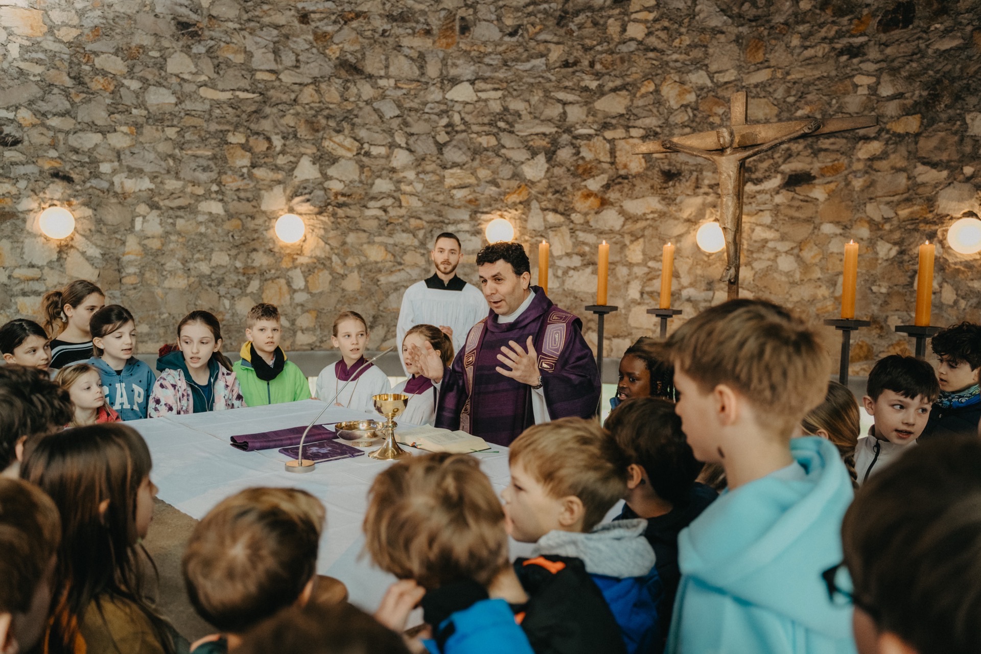 Priester erklärt Kindern Messe am Altar