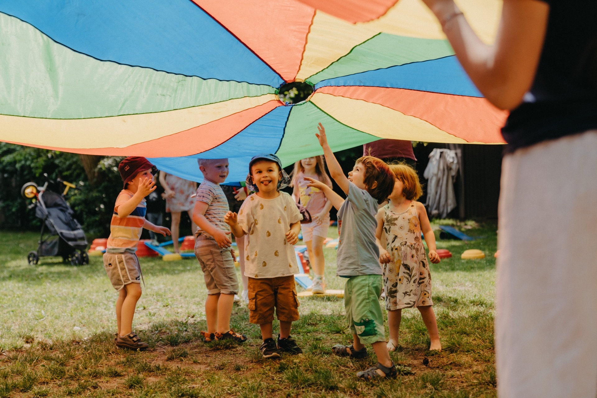 Kinder spielen unter buntem Schwungtuch im Garten