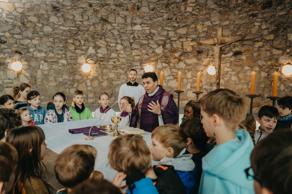 Pfarrer spricht zu Kindern in einer Kirche.