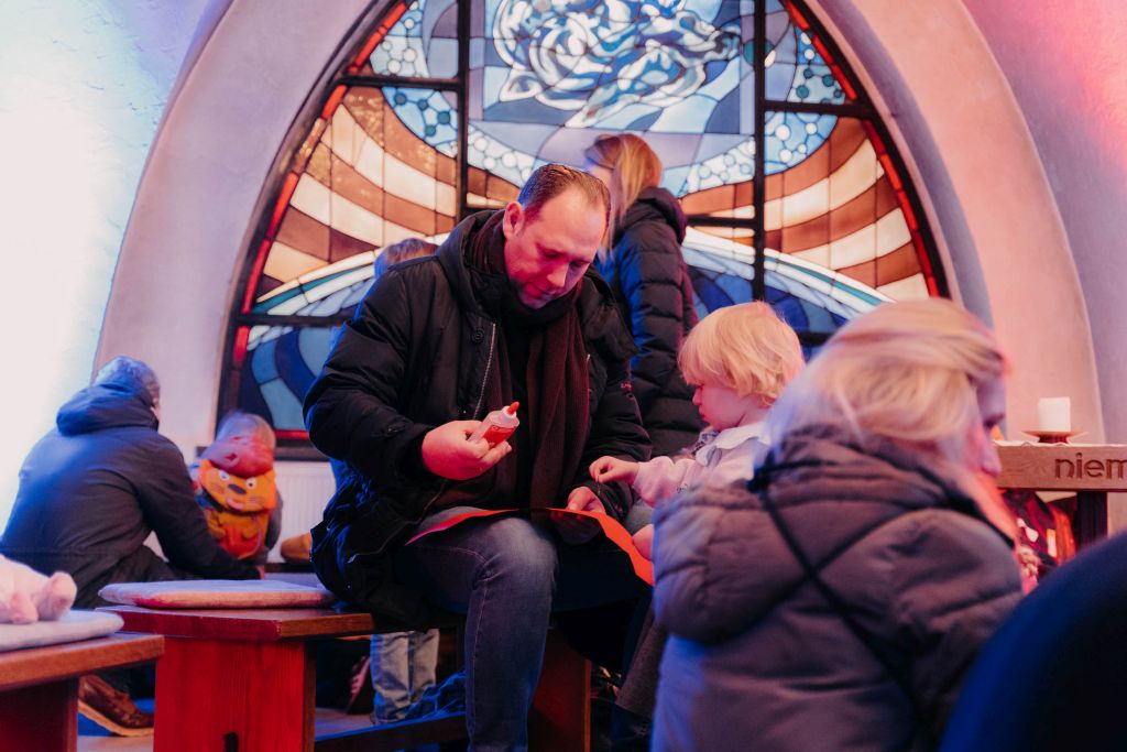 Menschen im Innenraum mit buntem Glasfenster