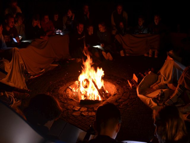 Menschen sitzen nachts gemeinsam am Lagerfeuer