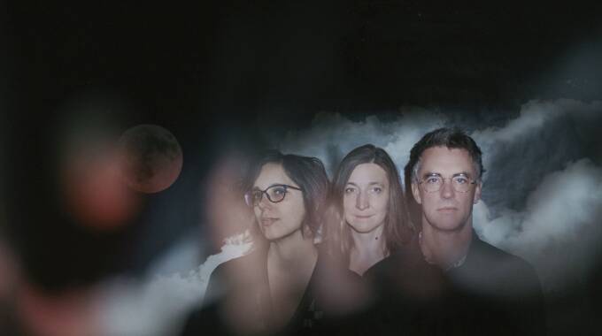 Drei Personen vor wolkigem Hintergrund mit Mond