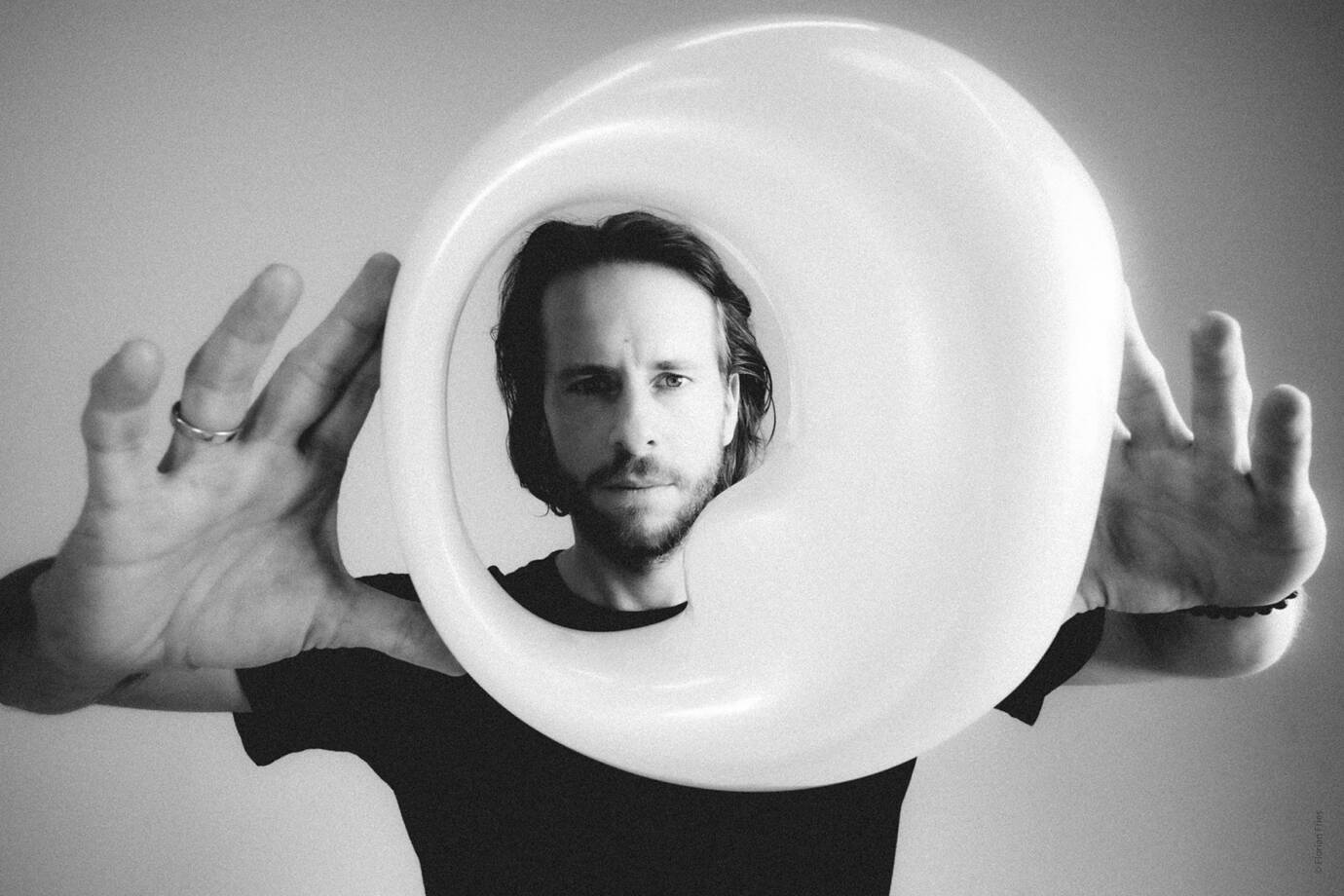 Person hält großes rundes Kunstobjekt vor Gesicht