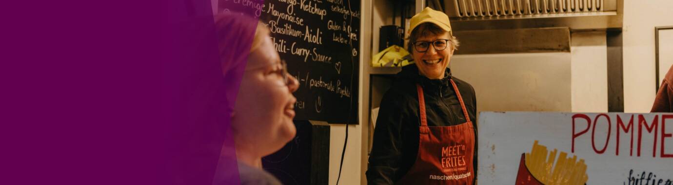 Verkäuferin serviert Pommes an glückliche Kundin