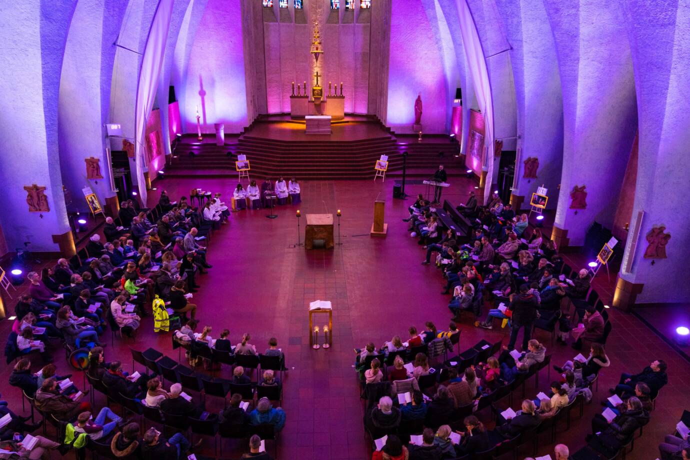 Gottesdienst in beleuchteter Kirche mit vielen Besuchern