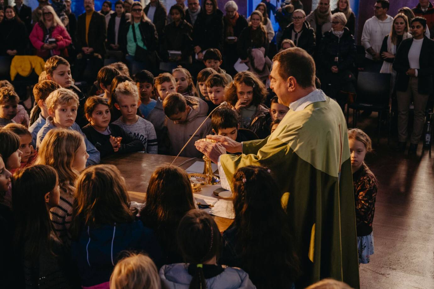 Priester feiert Messe mit Kindern in Kirche