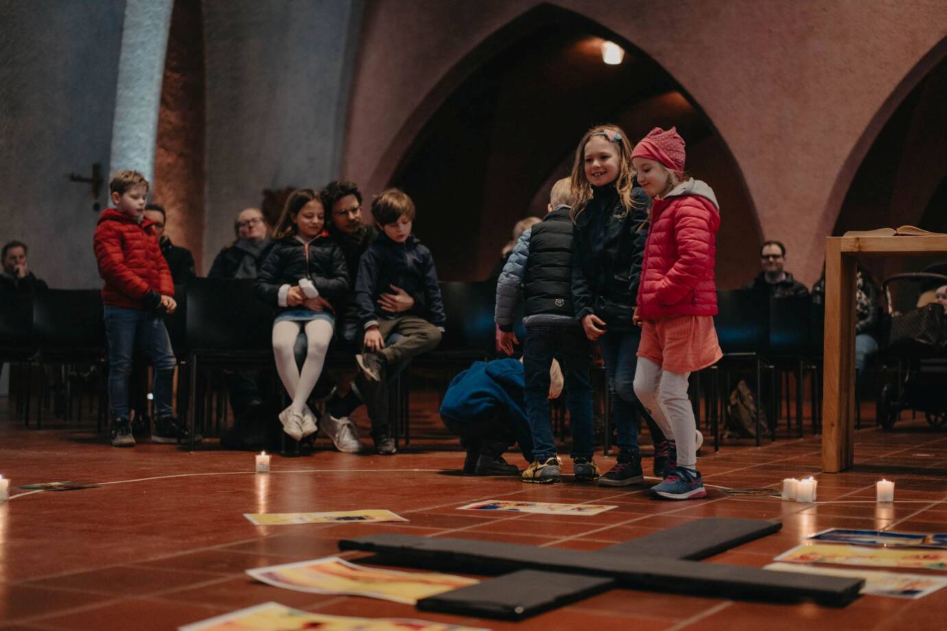 Kinderaktivität in einer Kirche mit Kerzen und Kreuz.