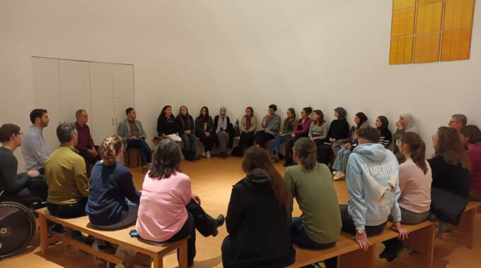 Gruppe von Menschen sitzt im Stuhlkreis im Raum