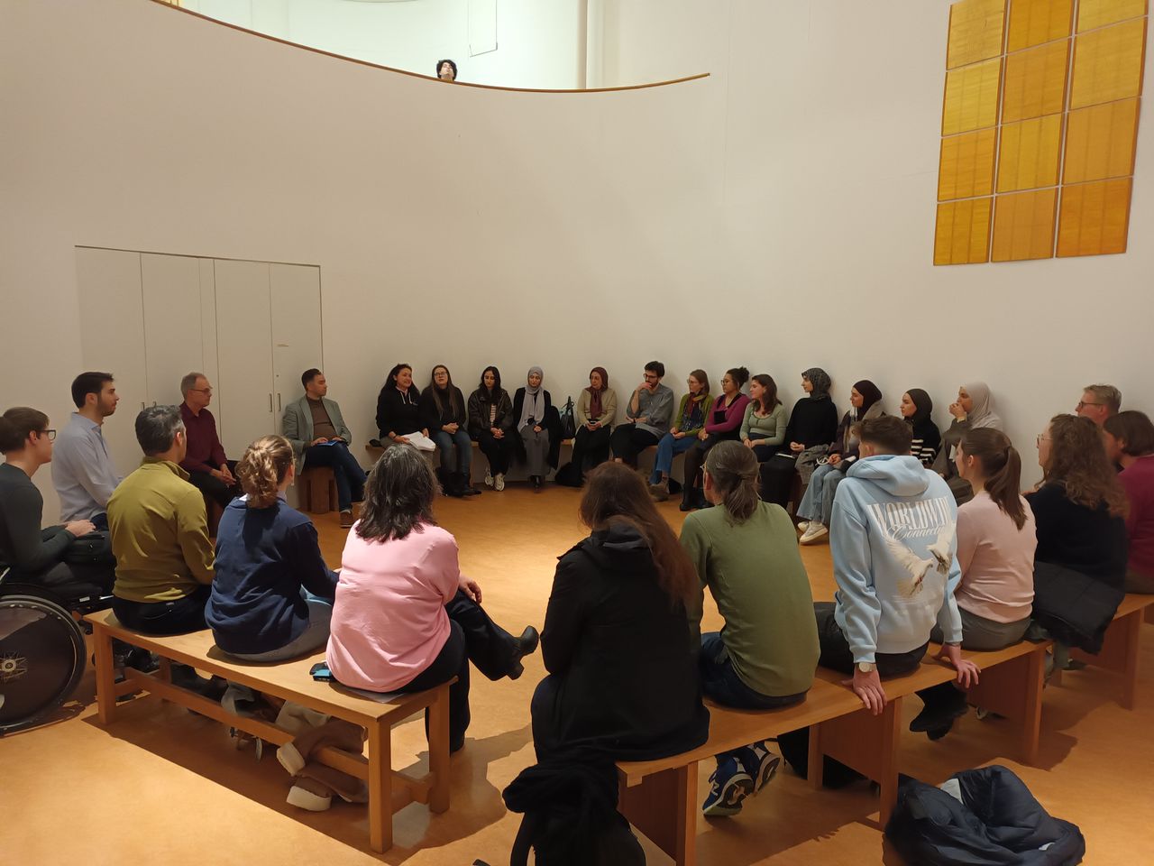 Gruppe von Menschen sitzt im Stuhlkreis im Raum