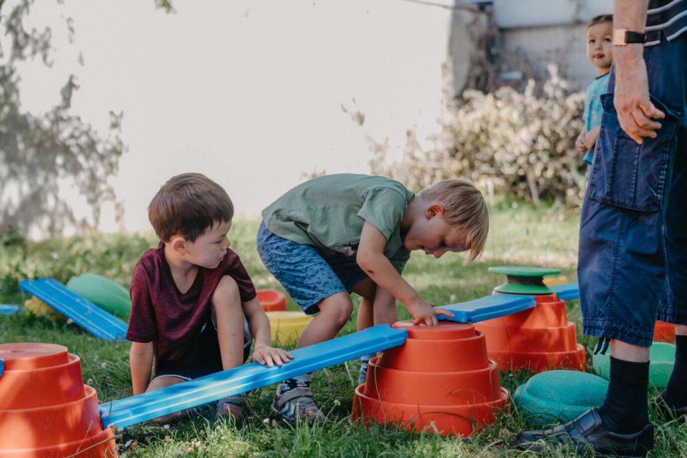 Kinder spielen draußen mit buntem Balancierparcours