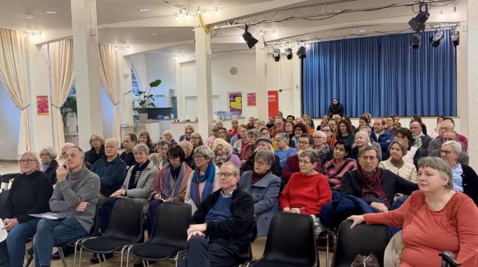 Menschen sitzen bei einer Veranstaltung im Saal.