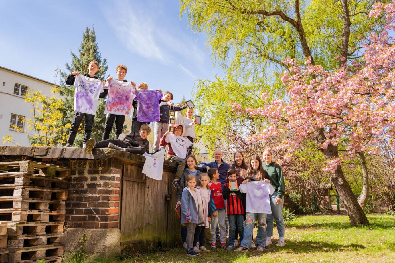 Kinder zeigen bemalte T-Shirts im Frühlingsgarten