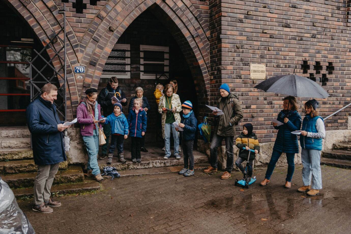 Gruppe singt gemeinsam vor einem Backsteingebäude