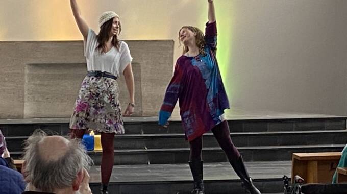 Zwei Frauen tanzen fröhlich auf einer Bühne.