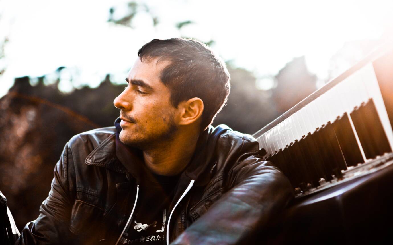 Mann mit Lederjacke neben einem Klavier draußen