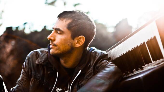 Mann mit Lederjacke neben einem Klavier draußen