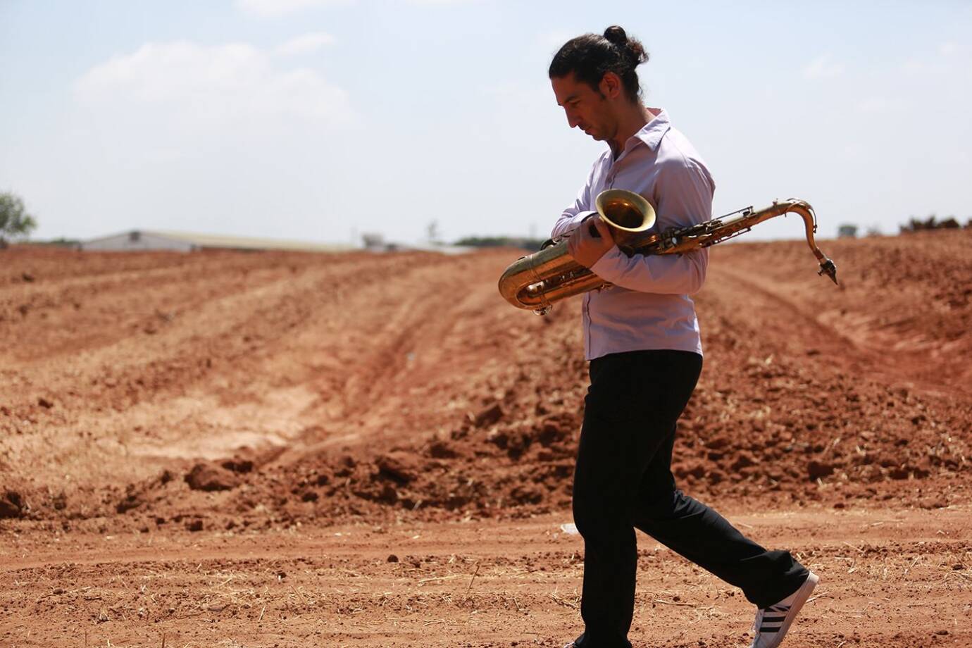 Person trägt Saxophon auf trockenem Feld