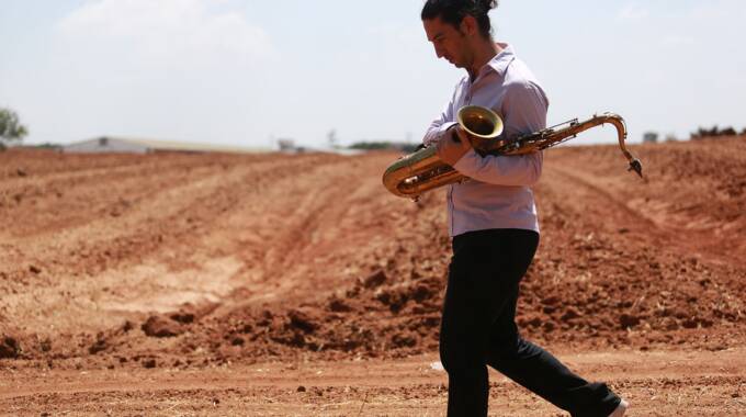 Person trägt Saxophon auf trockenem Feld