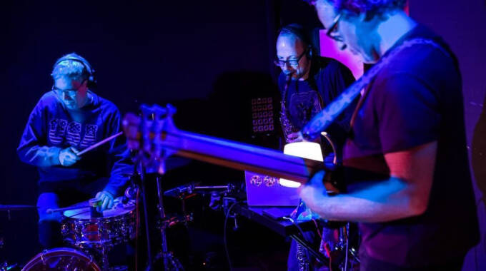 Drei Musiker spielen auf Bühne im blauen Licht