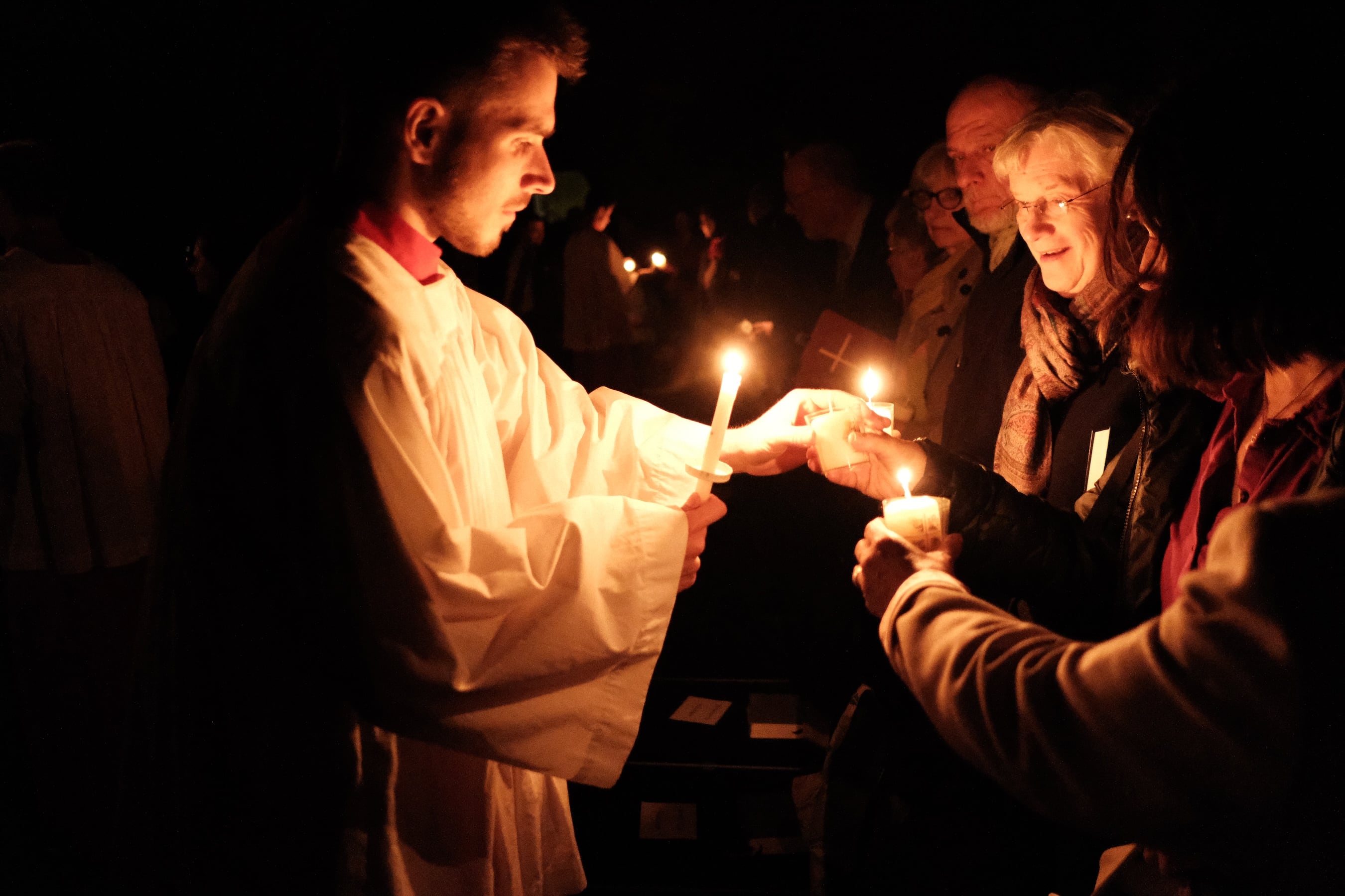 Ministrant zündet Kerze bei Osternacht an