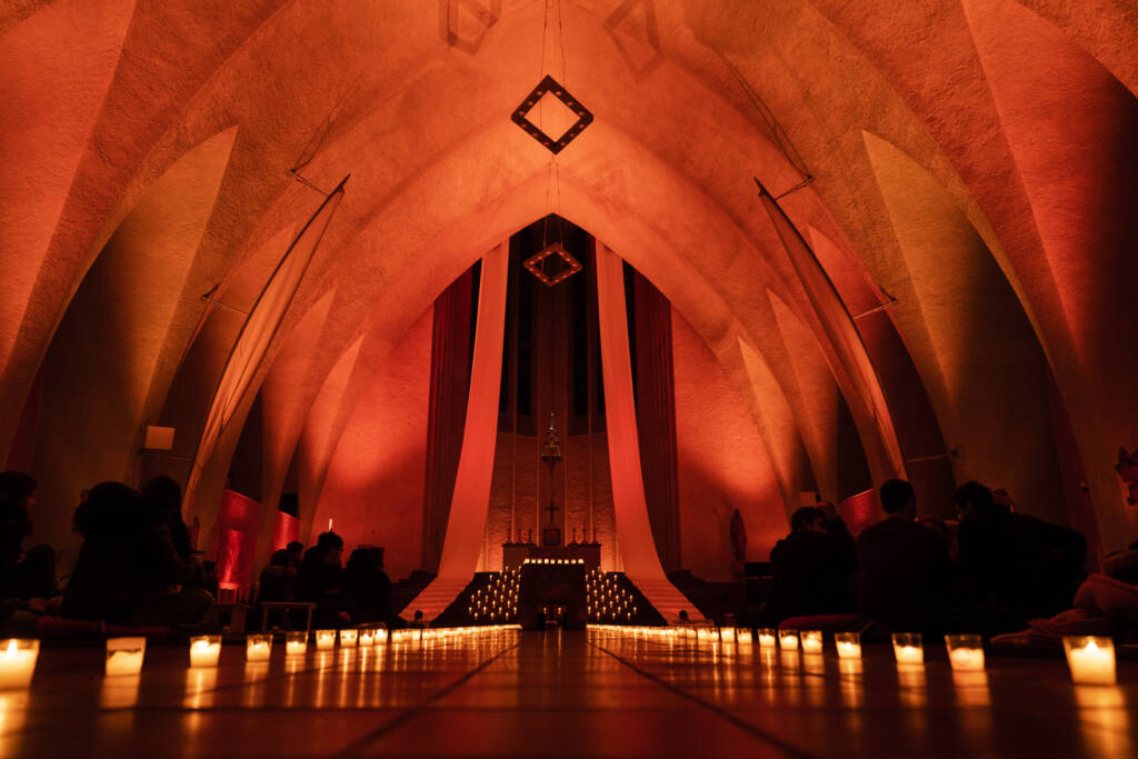 Kircheninnenraum mit roter Beleuchtung und Kerzen