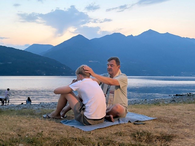 Mann tröstet Jungen am See bei Sonnenuntergang